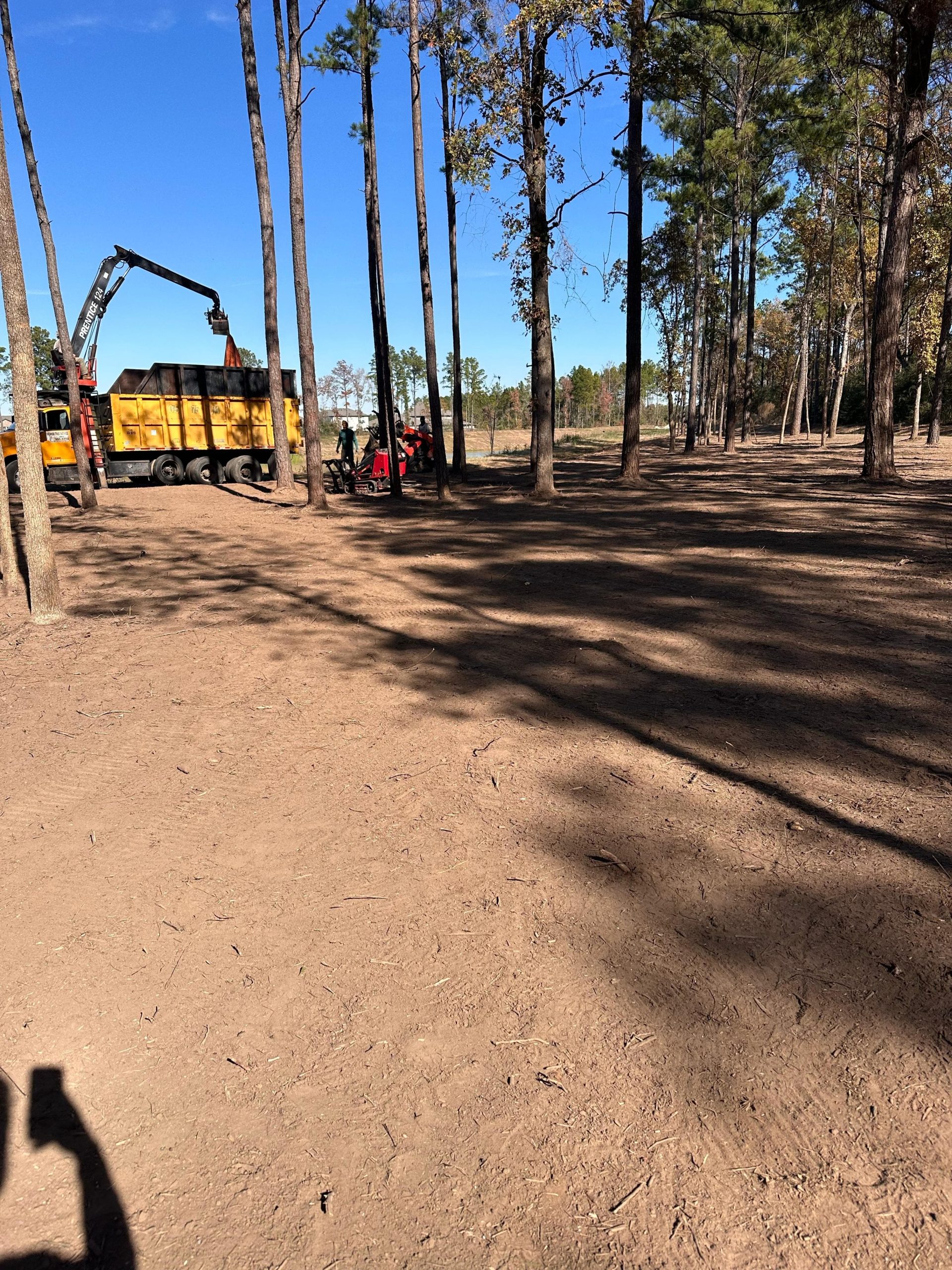 Heavy equipment and a truck parked on a dirt road during a land clearing project.